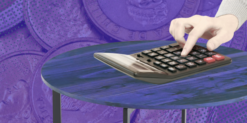 imagen de una calculadora sobre una mesa. El fondo son monedas