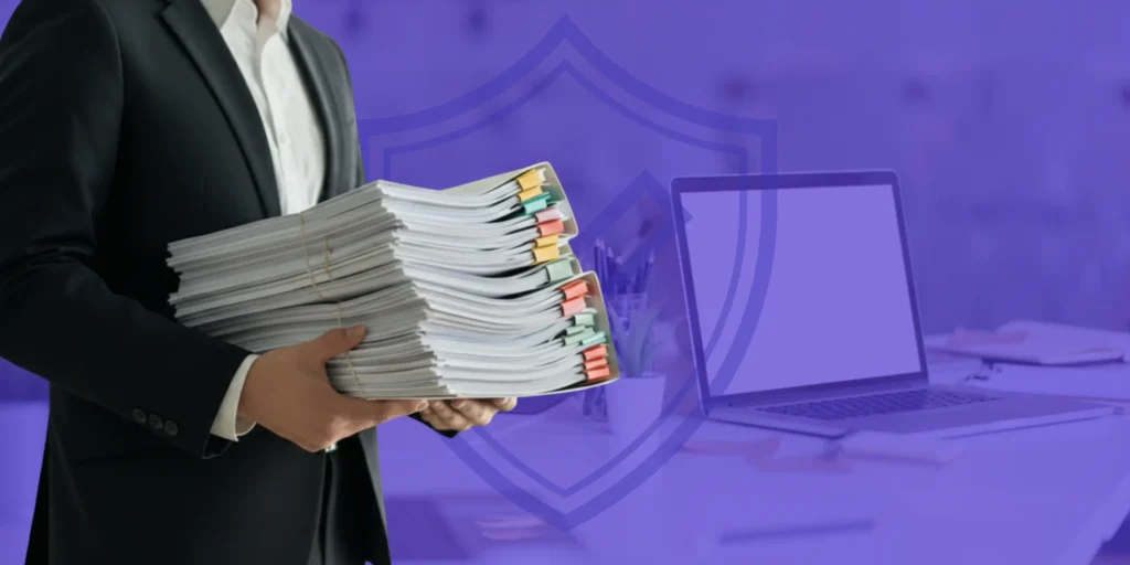 Un profesional en traje sosteniendo una voluminosa pila de documentos legales junto a un computador y un escudo protector de fondo, representando el procedimiento de renegociación de deudas.